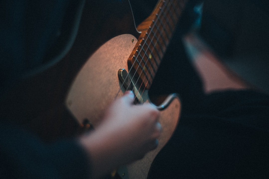 person playing brown acoustic guitar