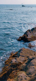 A scenic view of a rocky island with waves gently crashing on the shore