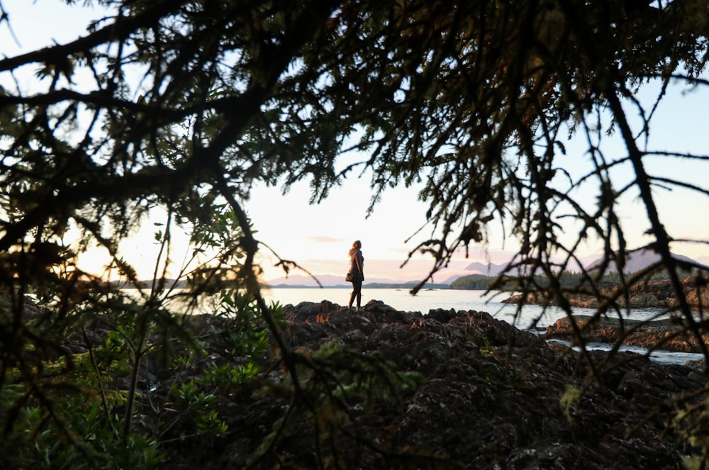 woman in black tank top and black pants standing on brown sand near body of water