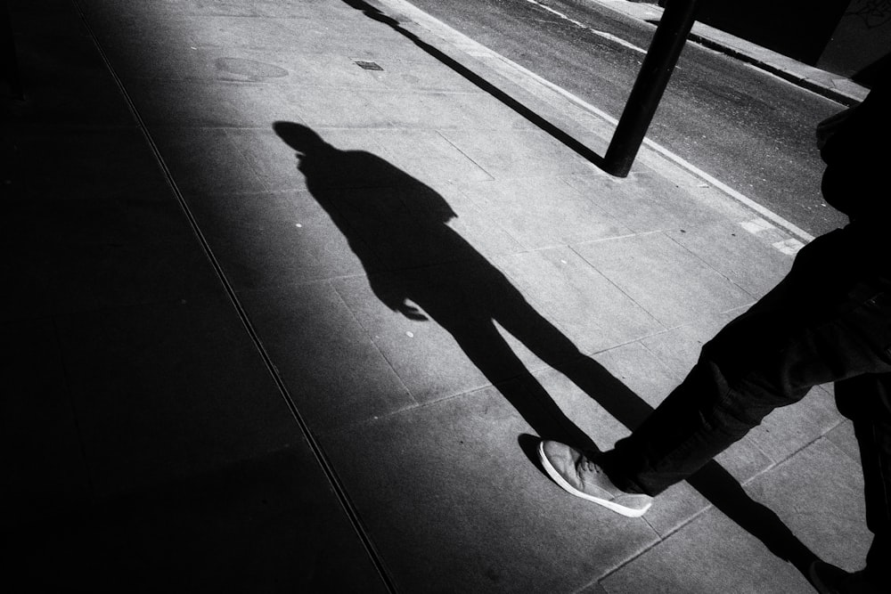 person in black pants and white and black nike sneakers walking on gray concrete floor