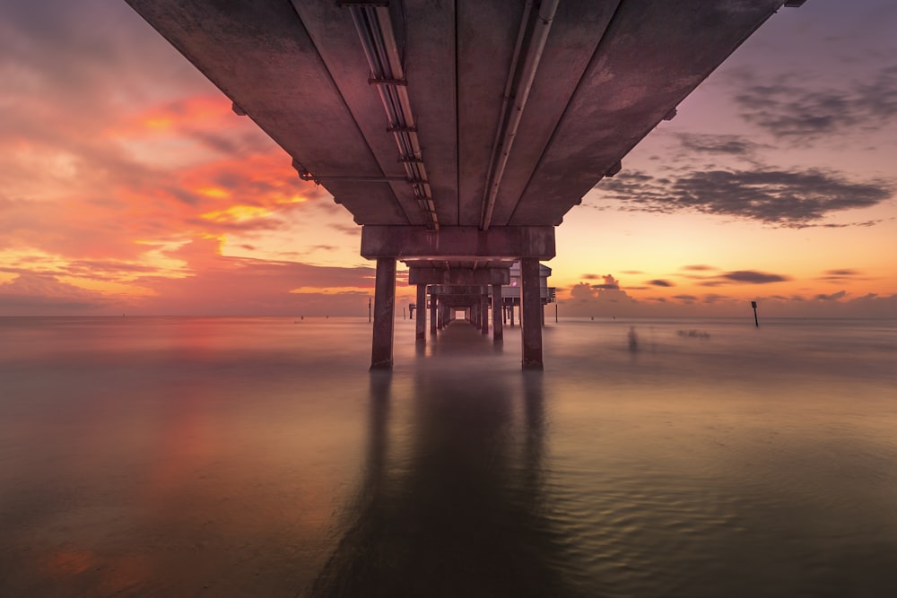 Puente de hormigón gris sobre el mar durante la puesta del sol