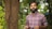 man in blue and red plaid dress shirt standing beside brown tree during daytime