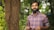 man in blue and red plaid dress shirt standing beside brown tree during daytime