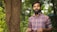 man in blue and red plaid dress shirt standing beside brown tree during daytime