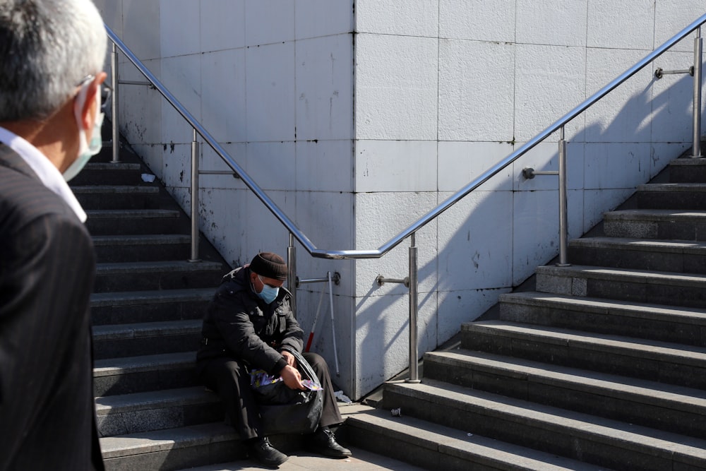 Mann in schwarzer Jacke sitzt auf der Treppe