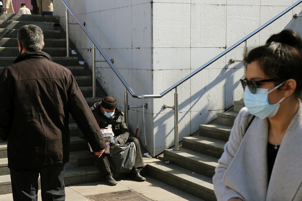 man in black jacket and gray pants walking on gray concrete stairs