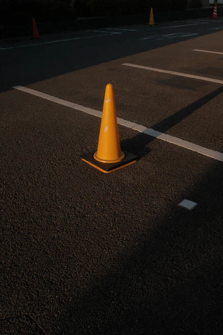 Commercial parking lot freshly sealed with dark orange safety cones along the edges