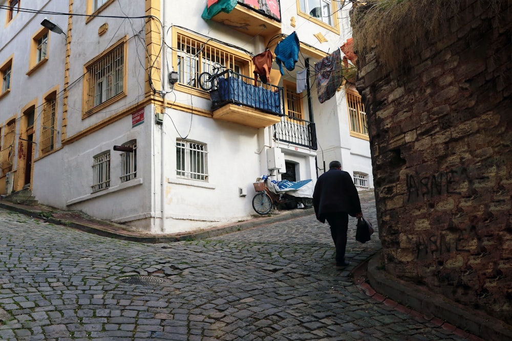 man in black jacket walking on sidewalk during daytime