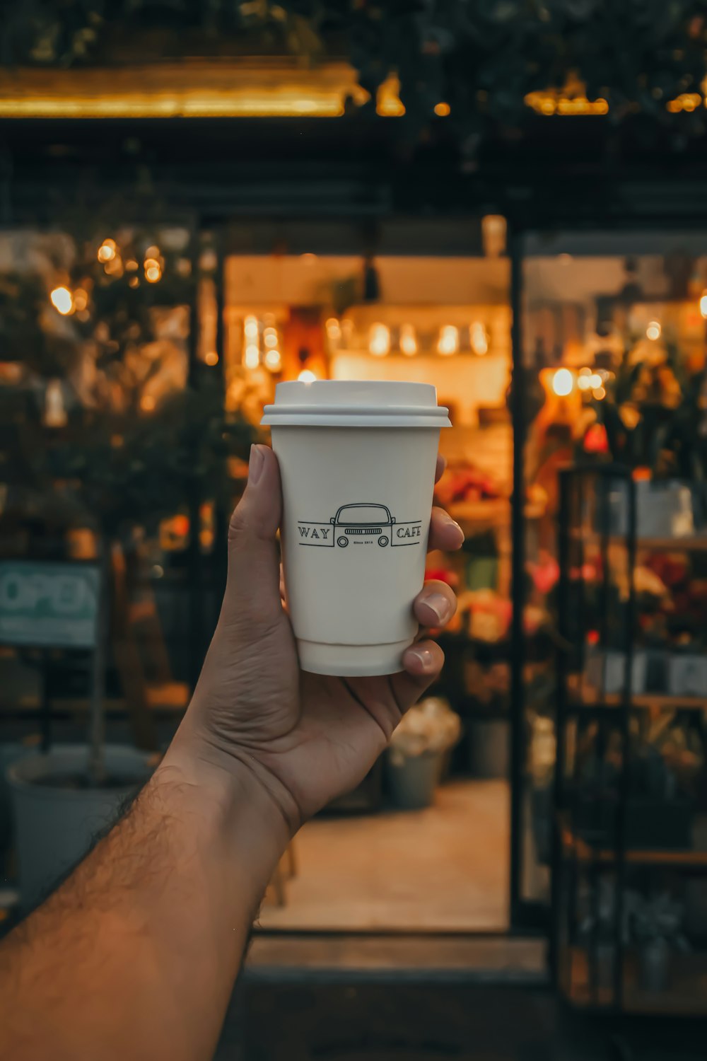 person holding white disposable cup