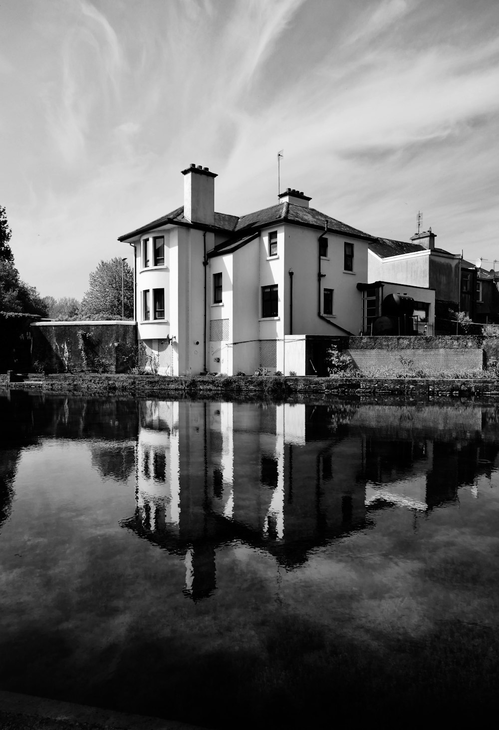 grayscale photo of house near body of water