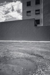 A minimalist black and white photo of an urban vacant lot with subtle blue and earth tones highlighting textures.