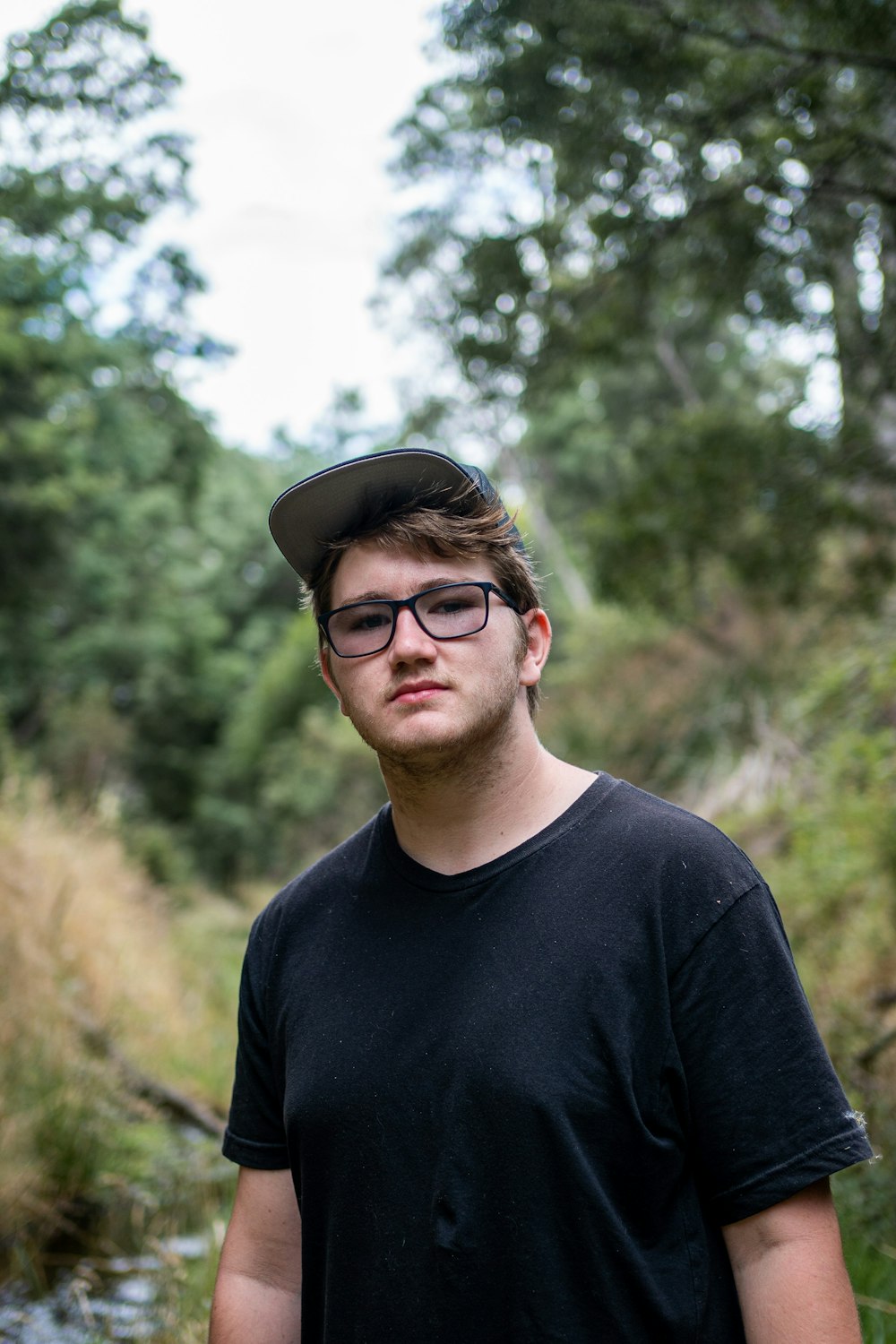 man in black crew neck shirt wearing black cap and black framed eyeglasses