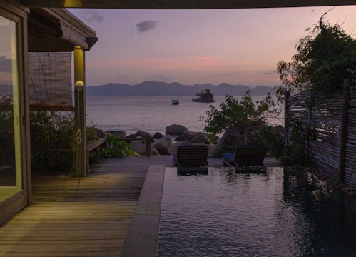A tranquil infinity pool overlooking natural greenery at sunset.