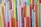 A collection of colorful plastic straws standing vertically, displaying a variety of shades including red, yellow, blue, and pink. The straws have ridged sections, and the arrangement creates a dense pattern.