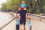 man in black t-shirt and brown shorts holding girl in blue and black jacket walking