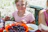 A smiling young girl holding her colorful insulated lunch bag and matching tableware at a picnic table.