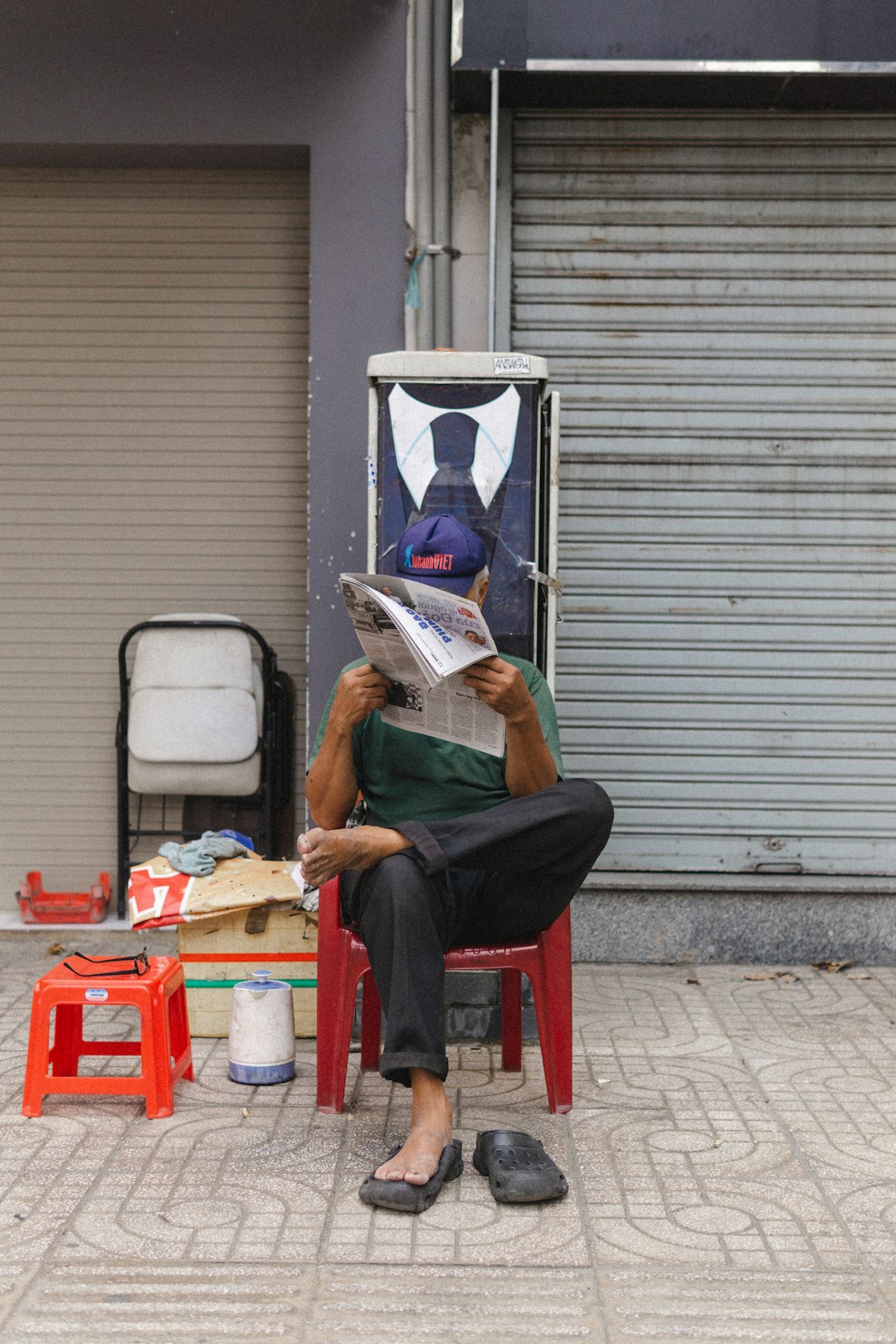 man in green t-shirt reading book sitting on red plastic chair