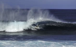 Surfer carving a massive wave at sunrise, water spraying with dynamic energy and motion.