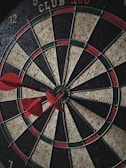 Close-up of darts hitting the bullseye on a brightly lit dartboard.