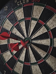 A close-up of a dart hitting the bullseye on a board.