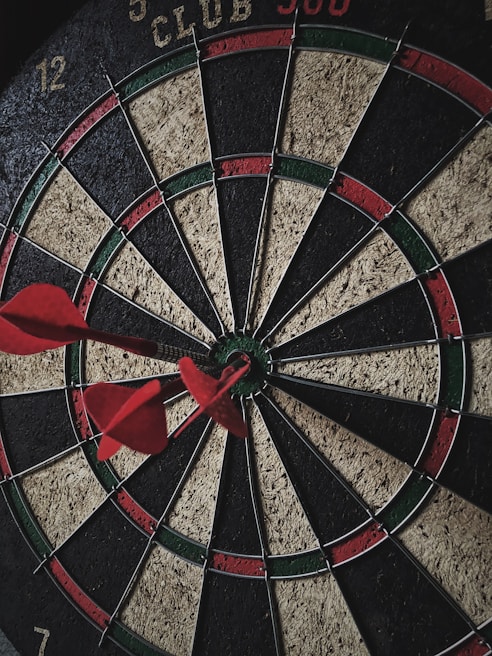 A close-up of a dartboard with colorful darts ready to be thrown.