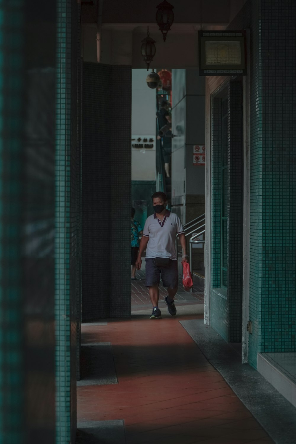 man in red jacket and blue denim jeans walking on hallway