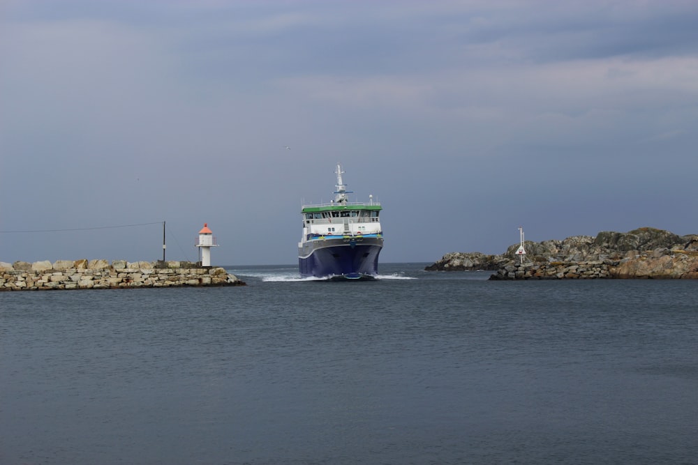 navire vert et blanc sur la mer sous le ciel gris pendant la journée