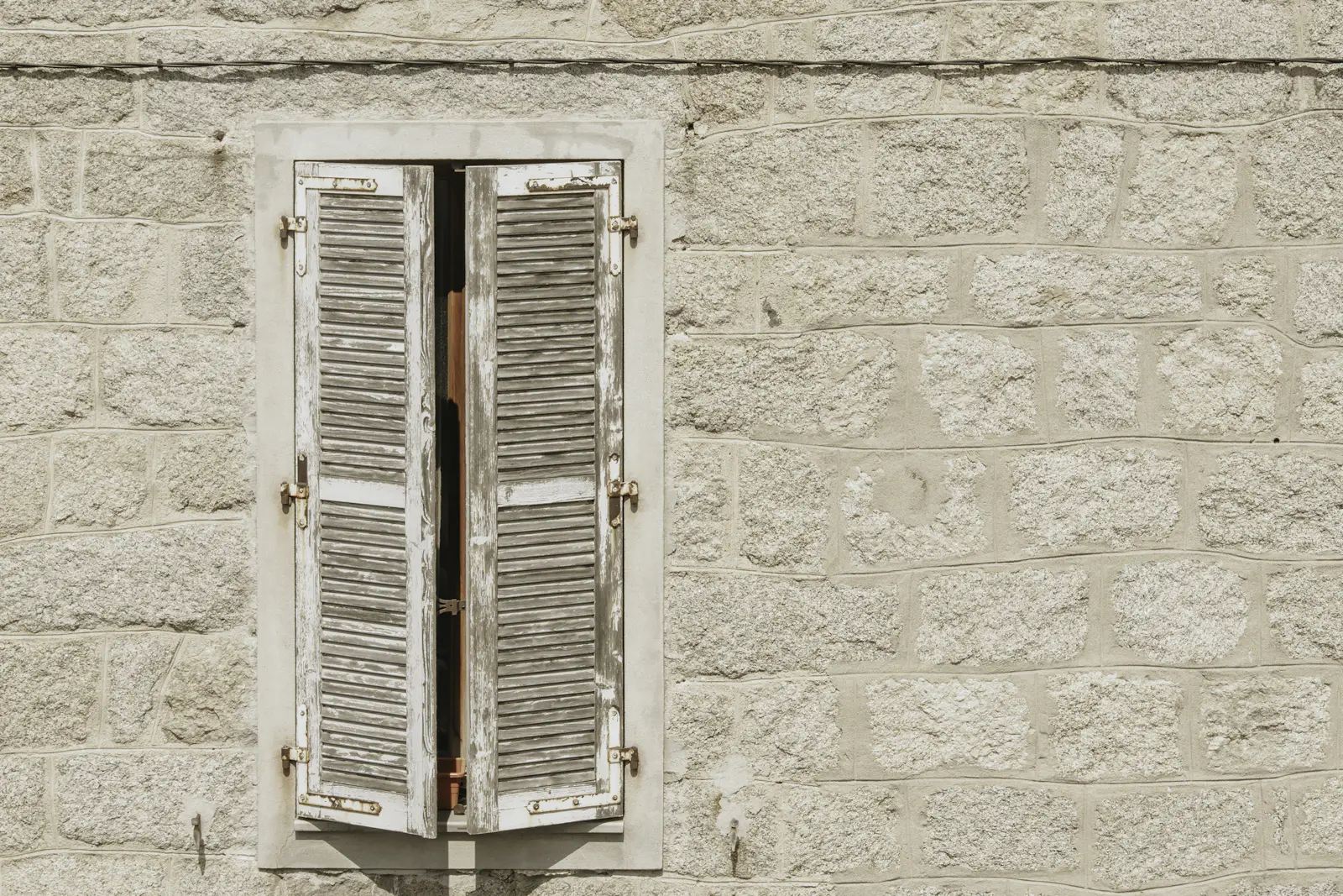 Volets en bois fermés sur la façade en pierre d'une maison méditerranéenne