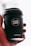 A hand is holding a black coffee cup with the logo 'CAFÉ LUX*' prominently displayed. The cup also features the text 'Ethically Sourced, Locally Roasted' and the website 'CAFELUX.MU'. The background is softly blurred, emphasizing the cup.