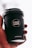 A hand is holding a black coffee cup with the logo 'CAFÉ LUX*' prominently displayed. The cup also features the text 'Ethically Sourced, Locally Roasted' and the website 'CAFELUX.MU'. The background is softly blurred, emphasizing the cup.