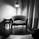 gray padded chair beside white wall