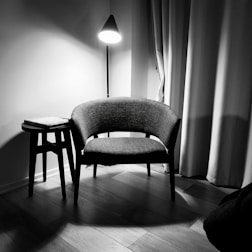 gray padded chair beside white wall