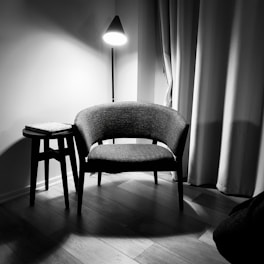 gray padded chair beside white wall