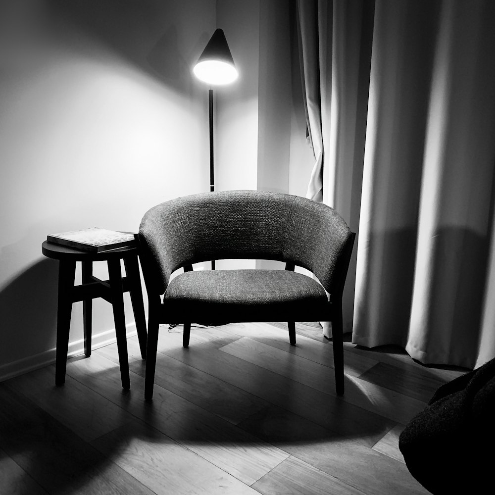 chaise rembourrée grise à côté d’un mur blanc