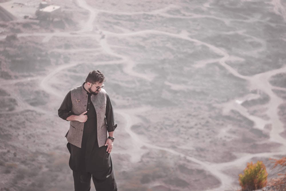 man in black coat standing on gray sand during daytime