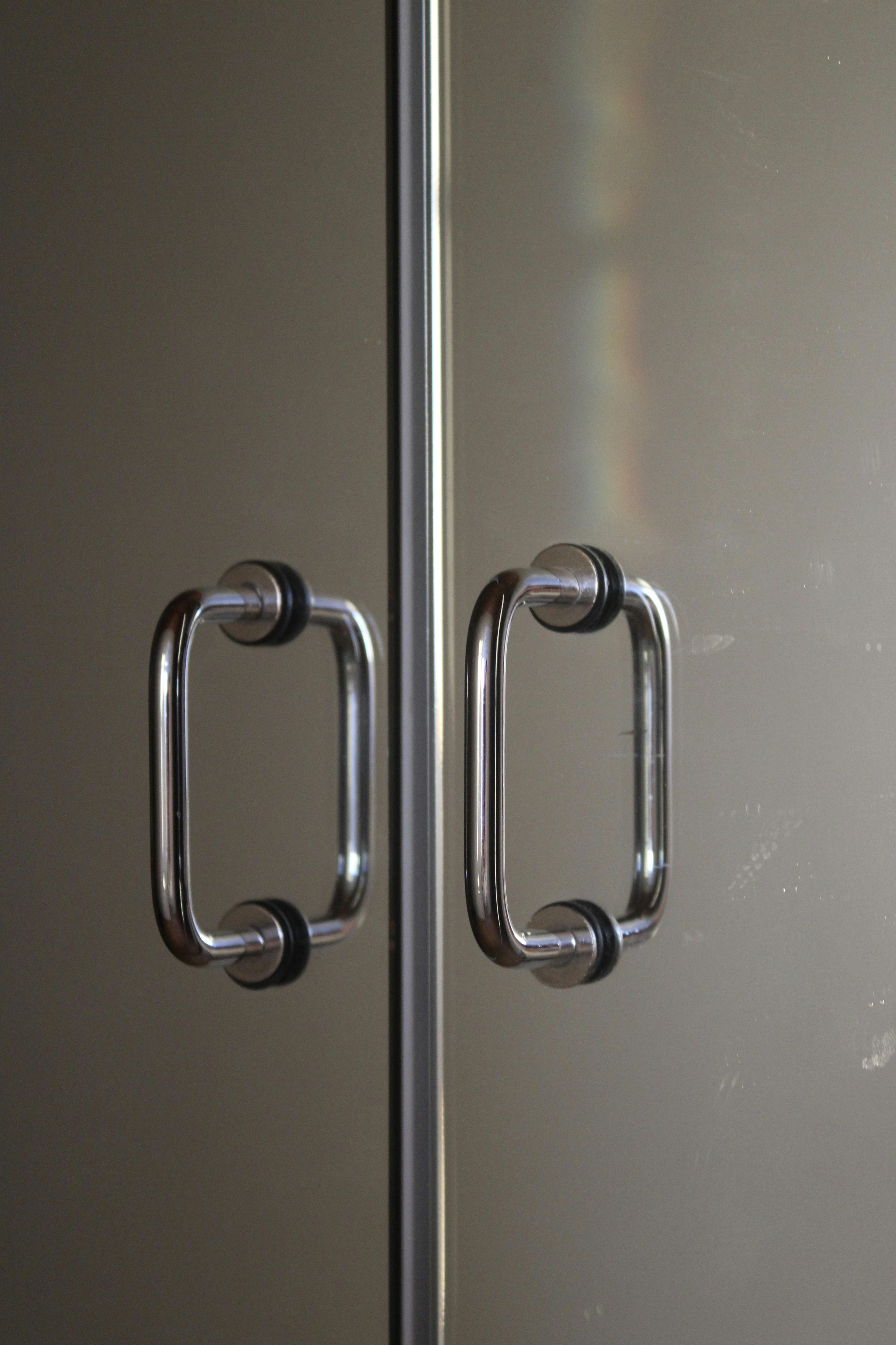 Shiny stainless steel door handles and locks arranged on dark surface with studio lighting showing metallic finish