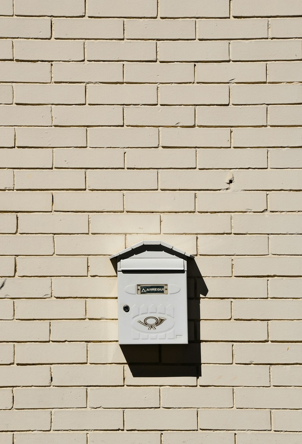 boîte aux lettres noire montée sur un mur de briques blanches