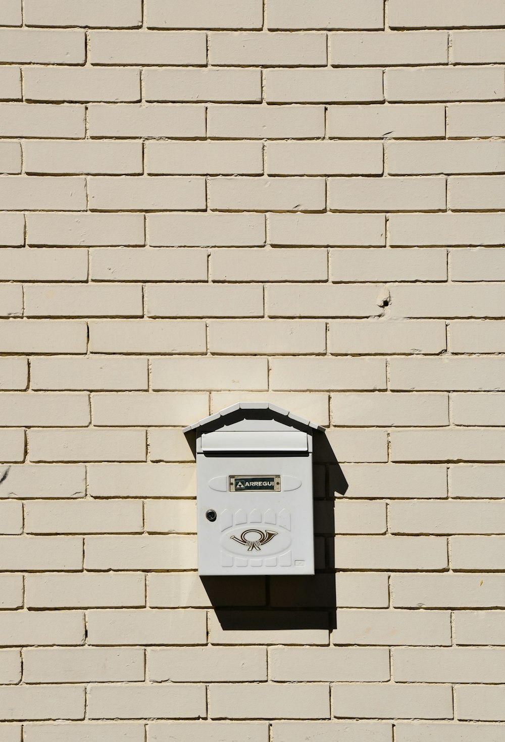 白いレンガの壁に取り付けられた黒い郵便ポスト