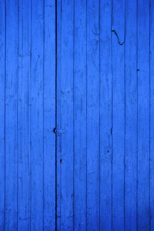 Close-up of vibrant exterior paint being applied on a wooden house wall.