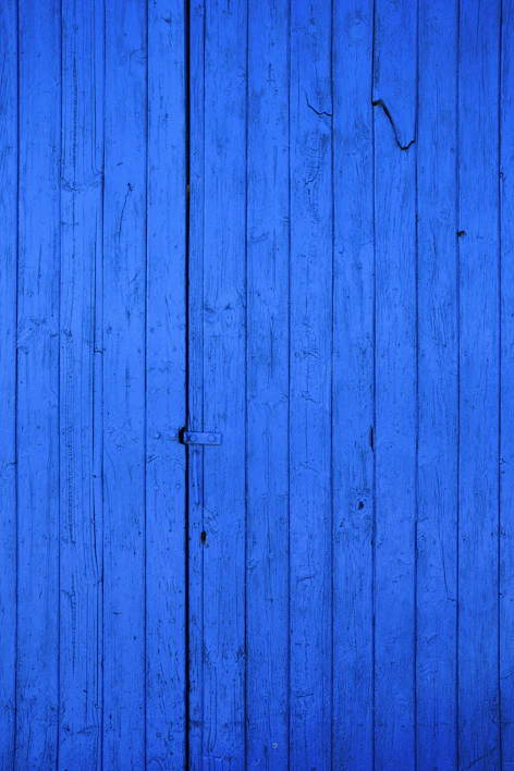 Close-up of vibrant exterior paint being applied on a wooden house wall.