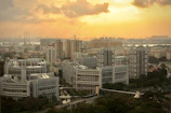 Wide-angle shot of a large residential complex at sunset with cranes in the background.