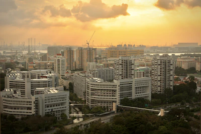 Wide-angle shot of a large residential complex at sunset with cranes in the background.