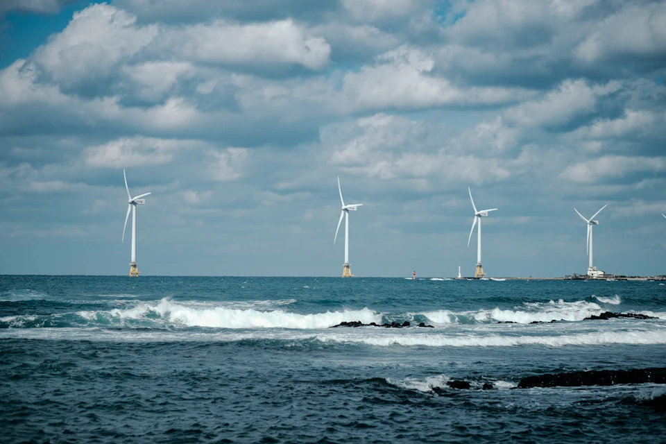 Six wind turbines stand tall on calm ocean waters, harnessing wind power generation