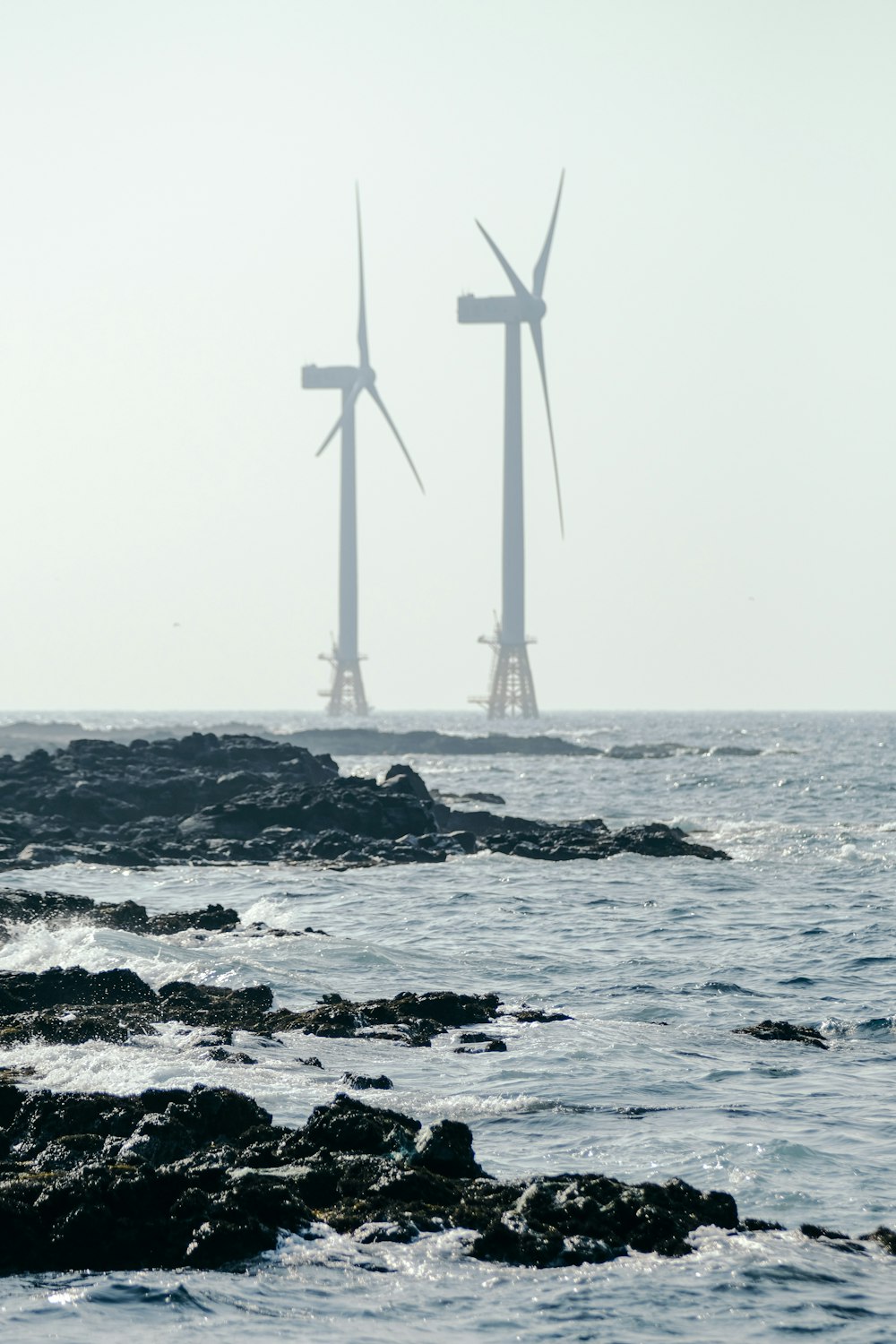 Weiße Windmühle am felsigen Ufer tagsüber