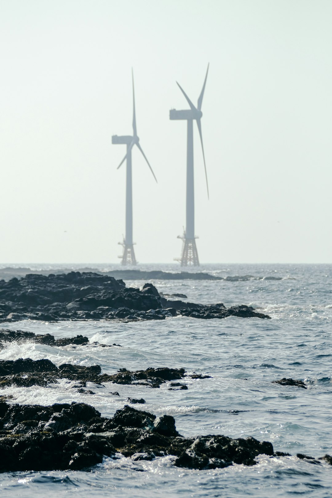 white wind mill on rocky shore during daytime