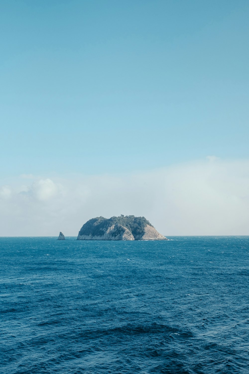 Formación rocosa negra y gris en el mar bajo el cielo azul durante el día