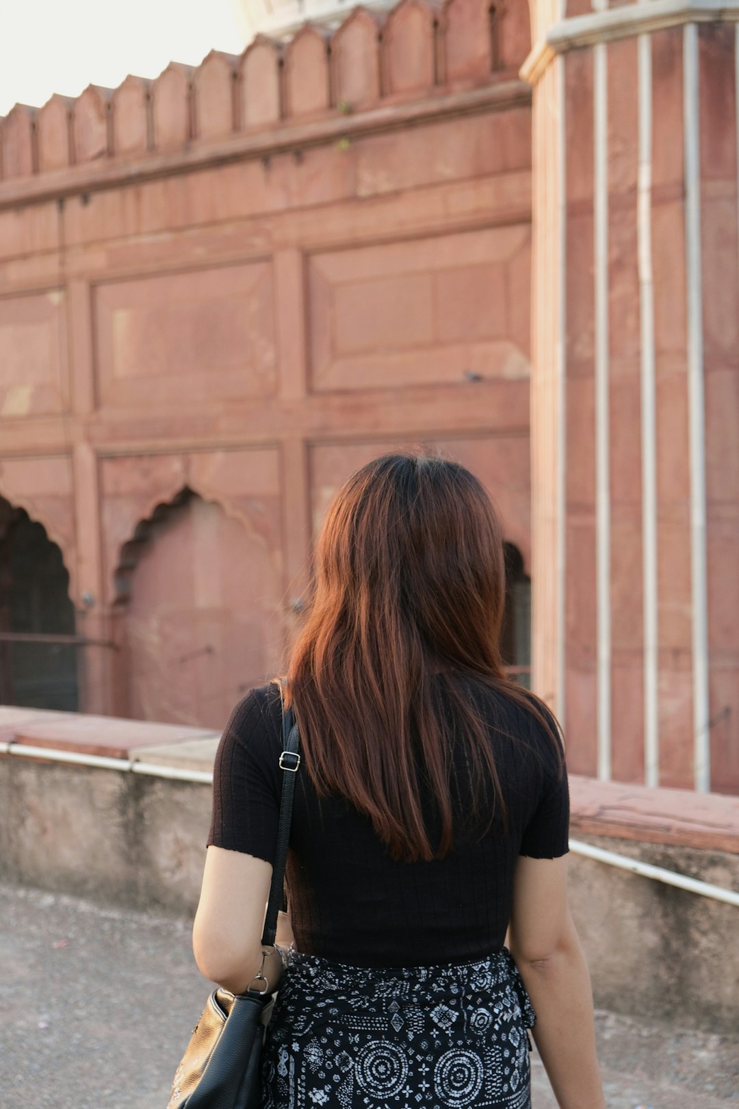 woman in black shirt standing near brown wooden wall during daytime