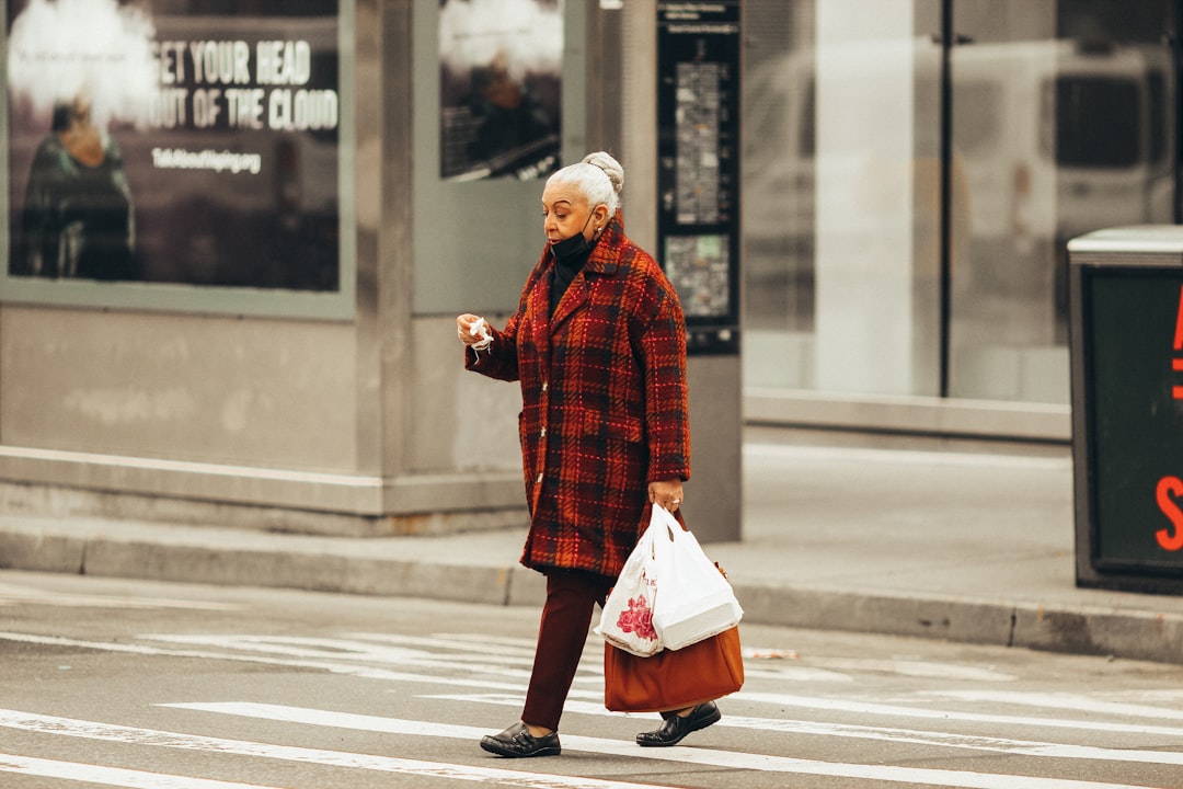man in red and black plaid dress shirt and white pants walking on pedestrian lane during