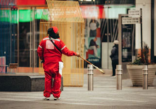 man in red jacket and pants walking on sidewalk during daytime