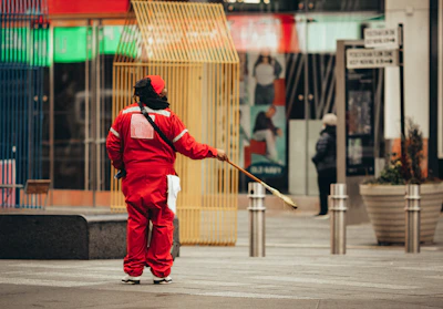 man in red jacket and pants walking on sidewalk during daytime